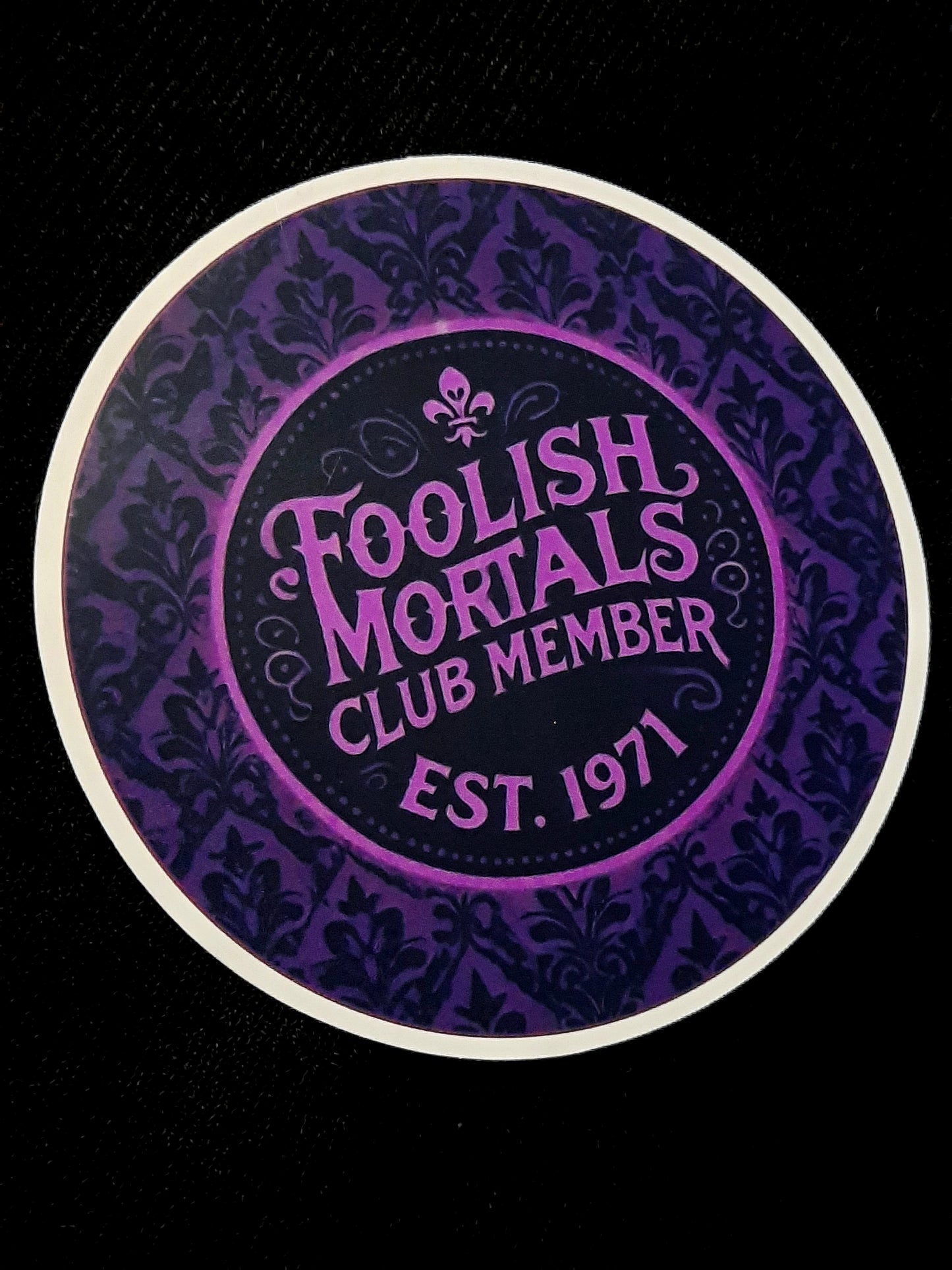 Round sticker with Foolish Mortals Club Member text on Haunted Mansion inspired background